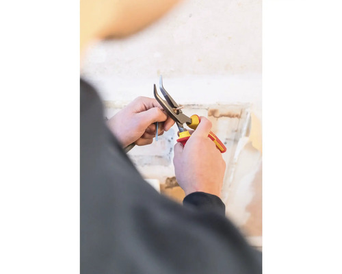 Osoba stříhá kabel kleštěmi