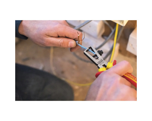 Osoba používá odizolovací kleště Stanley k odstranění izolace z kabelu.