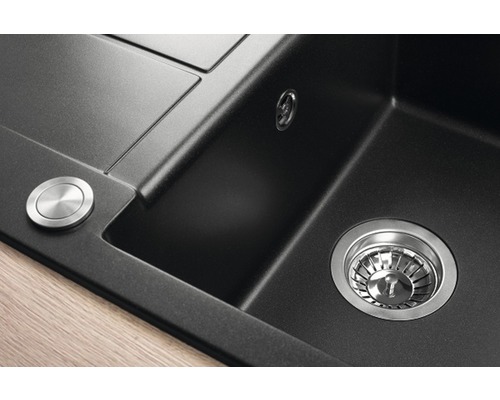 Detailní pohled na černý kuchyňský dřez se sítkovým ventilem a otočným knoflíkem