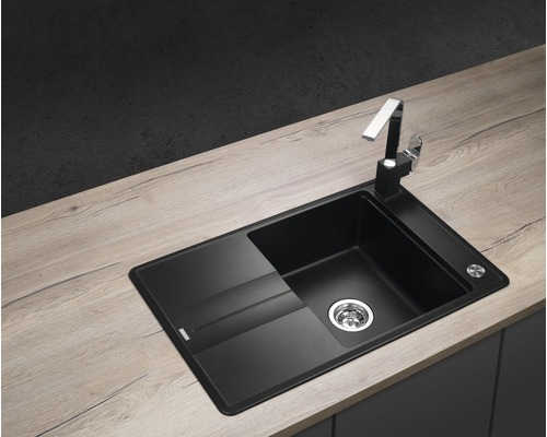 Černý kuchyňský dřez s odkapávací plochou a vodovodní baterií na pracovní desce