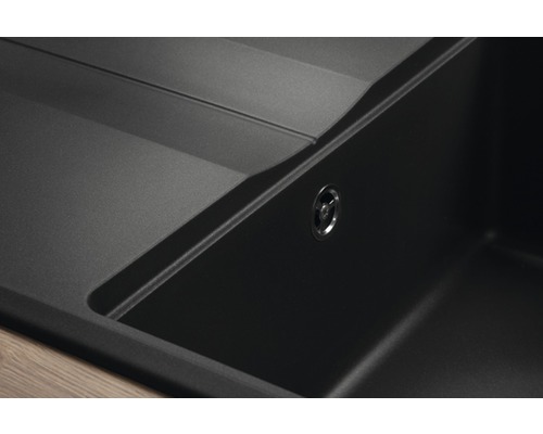 Detailní pohled na černý kompozitní kuchyňský dřez s odtokem