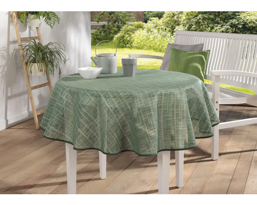 Zahradní scéna s kulatým stolem se zeleným ubrusem, nádobím a bílou zahradní lavicí