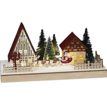 Dekorativní vánoční krajina s domy, jedlemi, soby a Santa Clausem na saních