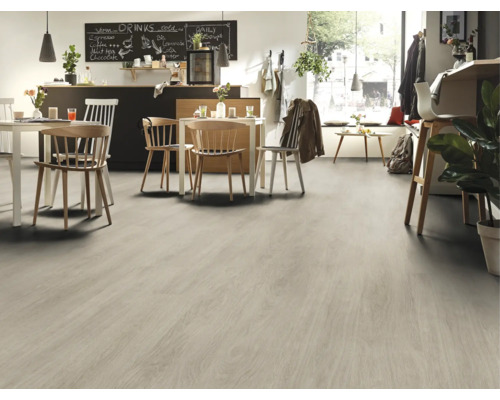 Světlá podlahová krytina ve světlé místnosti se stoly a židlemi.