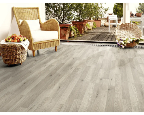 Světlá dřevěná podlaha v obývacím pokoji s proutěným křeslem a dekorací