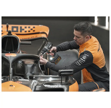 Muž připevňuje něco k závodnímu vozu pomocí akumulátorového šroubováku.