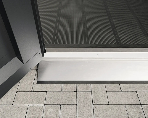 Detail prahového profilu mezi dveřmi a dlažebními kostkami.