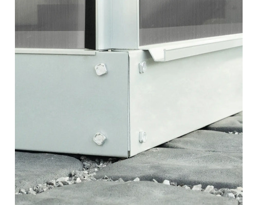 Detailní pohled na základ skleníku se šrouby na kamenné podlaze