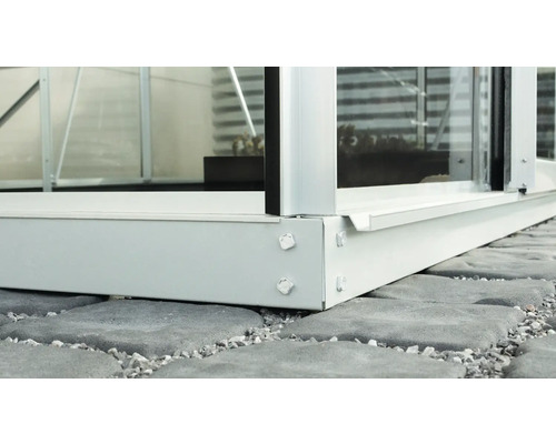 Detailní pohled na skleník se základovým rámem na kamenné podlaze