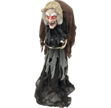 Dekorativní halloweenská čarodějnice se zářícíma očima a miskou v rukou.