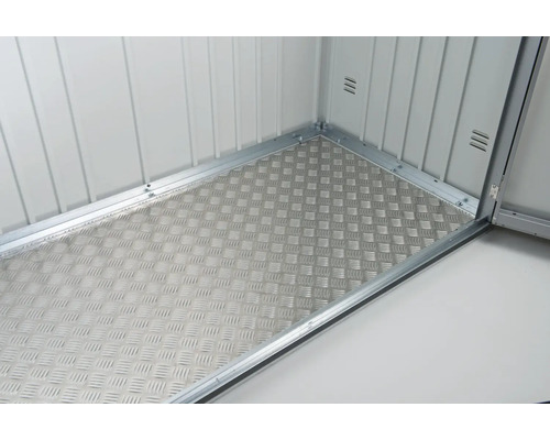 Pohled do kůlny na nářadí s podlahou z vlnitého plechu.