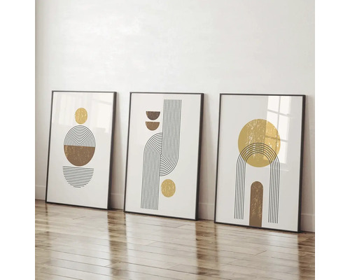 Tři zarámované umělecké tisky s abstraktními geometrickými tvary opřené o zeď