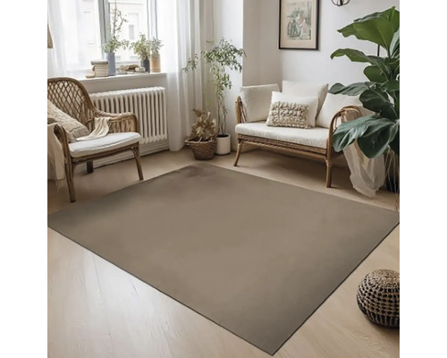 Obývací pokoj s kobercem, ratanovým křeslem a pohovkou ve světlém designu.