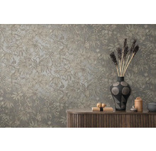 Dekorativní stěna s tropickým rostlinným vzorem nad dřevěnou skříňkou s vázami a dekorativními předměty.