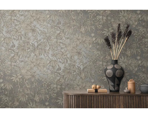 Dekorativní stěna s tropickým rostlinným vzorem nad dřevěnou skříňkou s vázami a dekorativními předměty.