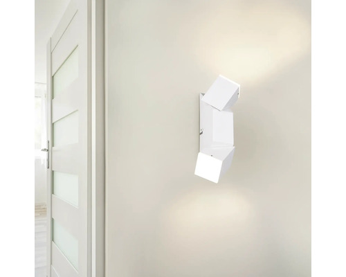 Bílé nástěnné svítidlo s moderním geometrickým designem a třemi kubickými hlavicemi.