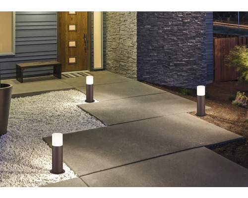 Osvětlený chodník s několika sloupkovými světly před domem.