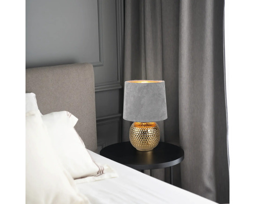 Dekorativní stolní lampa se stínidlem na nočním stolku v ložnici.