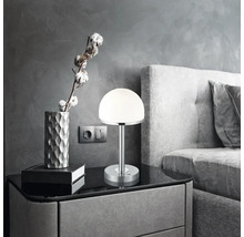 Noční stolek s lampou, dekorací a postelí v ložnici