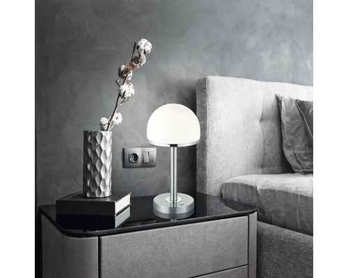 Noční stolek s lampou, dekorací a postelí v ložnici