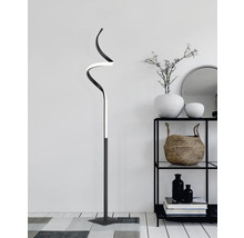 Dekorativní stojací lampa se zakřiveným designem v obývacím pokoji vedle regálu.