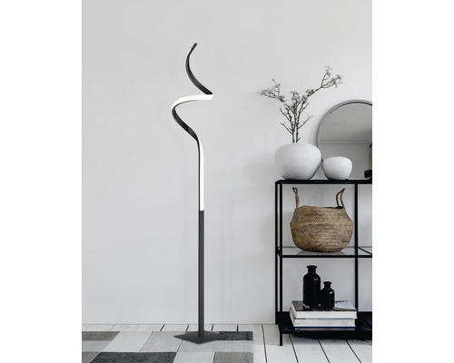 Dekorativní stojací lampa se zakřiveným designem v obývacím pokoji vedle regálu.