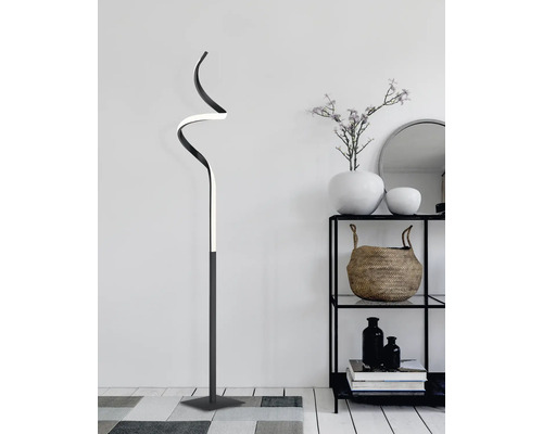 Zakřivená stojací lampa vedle regálu s dekorací