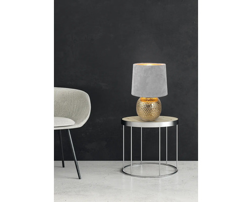 Dekorativní stolní lampa s textilním stínidlem na odkládacím stolku vedle židle