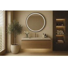 Moderní koupelna s umyvadlem, kulatým zrcadlem s osvětlením a dekoracemi.