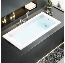 Moderní koupelna se zapuštěnou vanou, armaturami a dekoracemi.