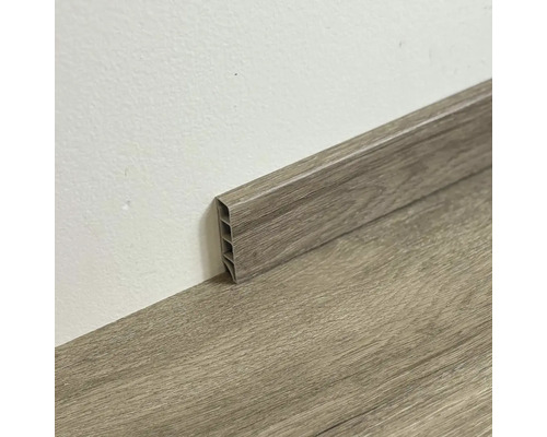 Plastová podlahová lišta s dřevěným vzhledem u zdi