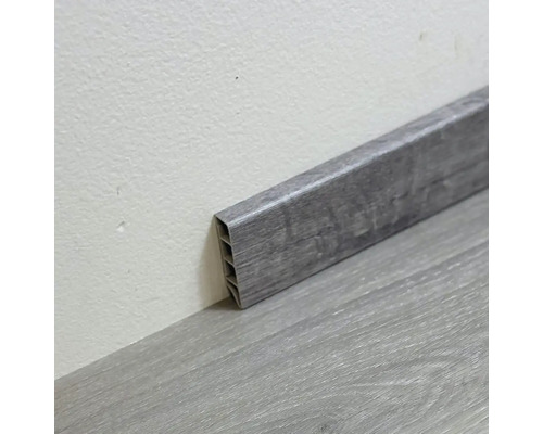 Šedá plastová podlahová lišta na podlaze a na stěně