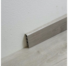 Plastová podlahová lišta s dřevěnou strukturou na stěně a podlaze