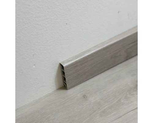 Plastová podlahová lišta s dřevěnou strukturou na stěně a podlaze