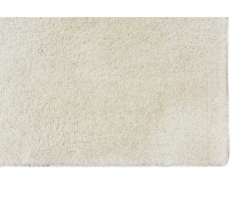 Detailní záběr na krémový koberec s vysokým vlasem a měkkou, hustou texturou.