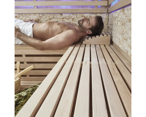 Muž relaxuje v sauně s dřevěnými lavicemi a příslušenstvím.