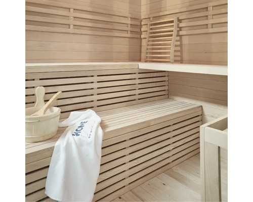 Světlá sauna s dřevěnými lehátky, dřevěným vědrem, naběračkou a ručníkem