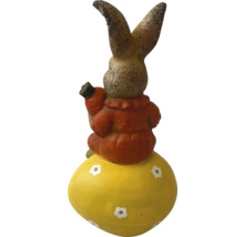 Dekorativní zajíc na velikonočním vejci s mrkví v ruce jako zahradní dekorace