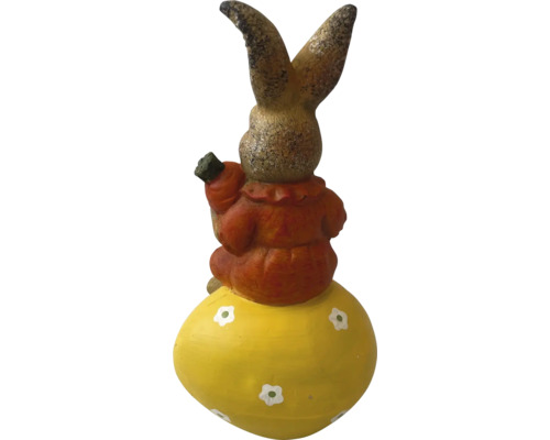 Dekorativní zajíc na velikonočním vejci s mrkví v ruce jako zahradní dekorace