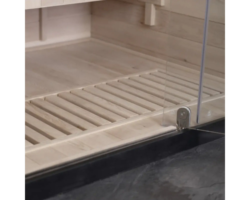 Detailní pohled do interiéru sauny s dřevěnou podlahou a skleněnými dveřmi