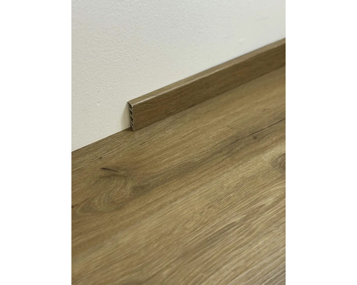 Dřevěná podlahová lišta na dřevěné podlaze u stěny