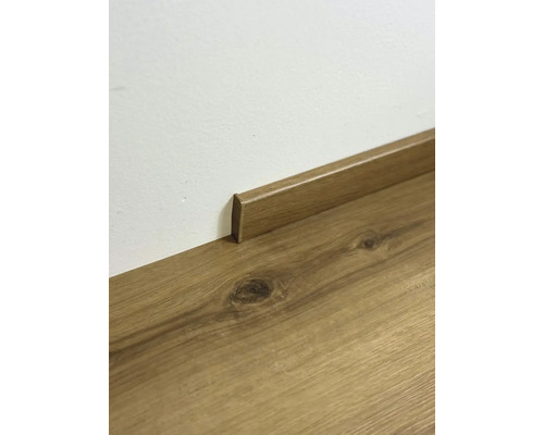 Dřevěná podlaha s odpovídající podlahovou lištou u zdi