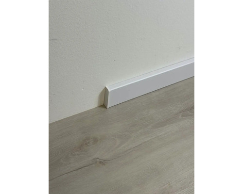 Bílá podlahová lišta na stěně nad podlahou