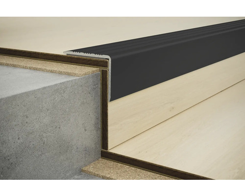 Detail schodové hrany s černým profilem na betonovém schodišti a laminátové podlaze.
