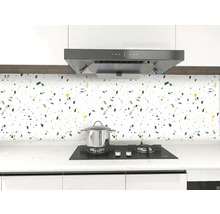 Kuchyňská scéna s dlaždicemi se skvrnitým vzorem, sporákem a odsavačem par.