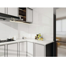 Světlá kuchyně s bílými obklady, kuchyňskými skříňkami a digestoří