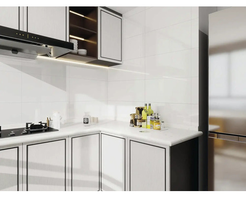 Světlá kuchyně s bílými obklady, kuchyňskými skříňkami a digestoří