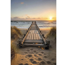 Dřevěná lávka vedoucí na pláž a k moři při západu slunce.