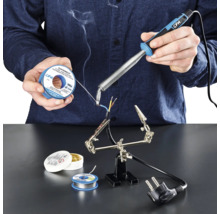 Osoba pájí kabely páječkou, pájecím cínem a pájecí pastou na pracovní ploše.