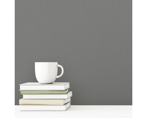 Šedá vliesová tapeta s textilní strukturou vedle šálku a knih